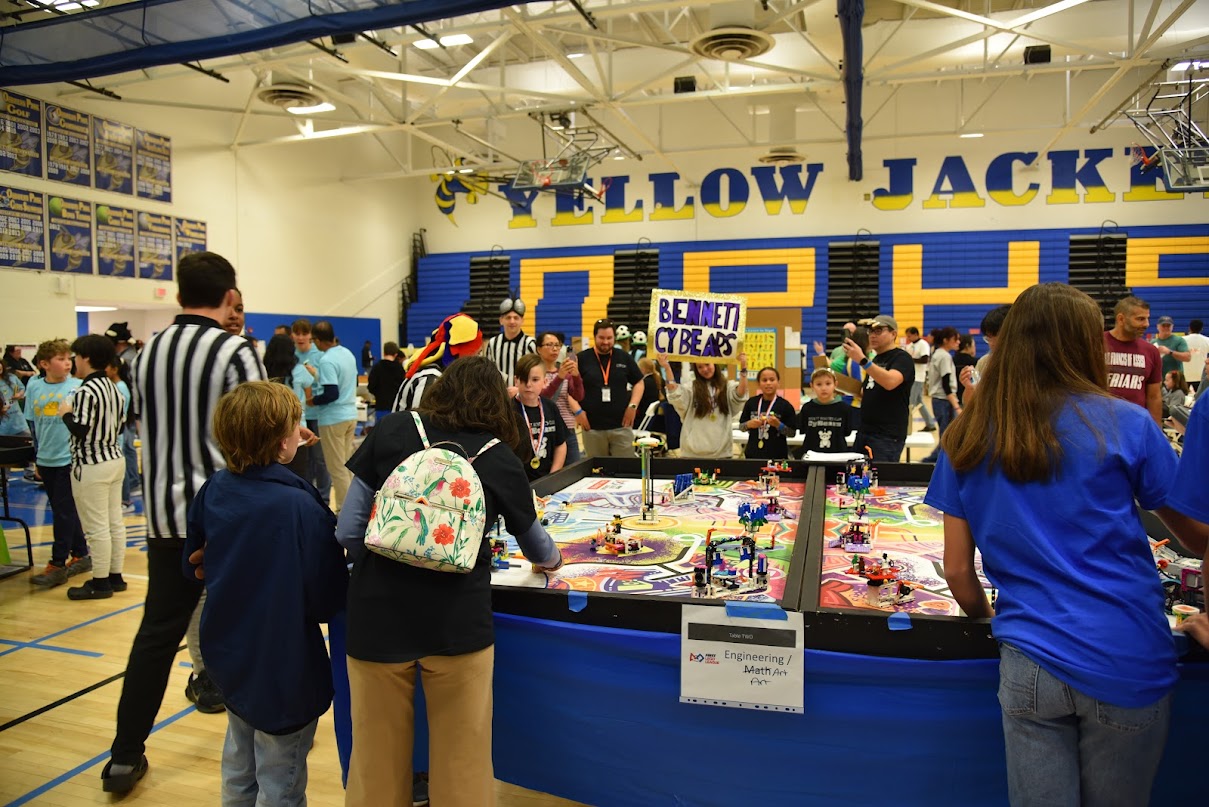 elementary school students standing around a competition table at a robotics competition